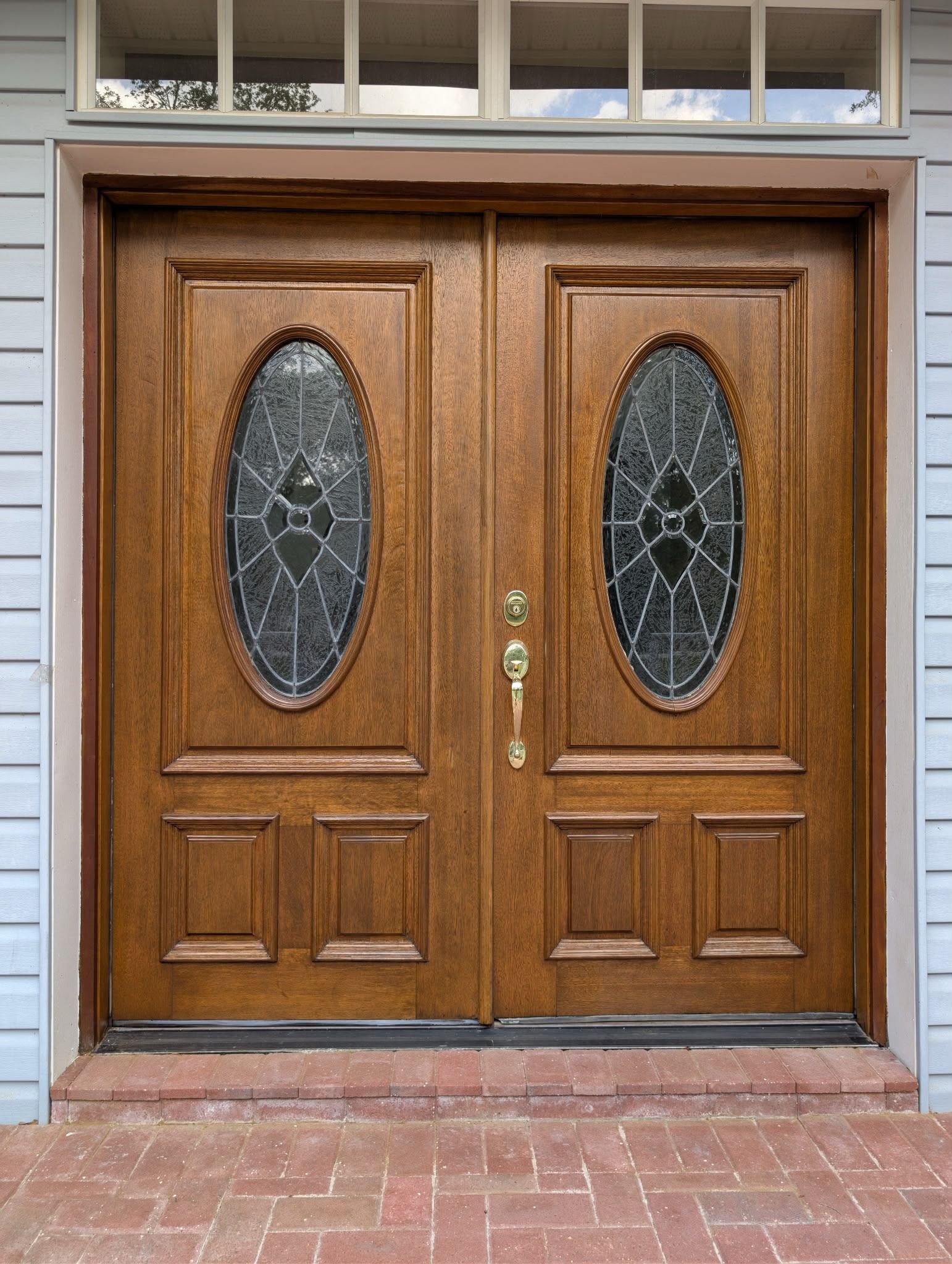 Restored double wooden front doors with oval leaded glass