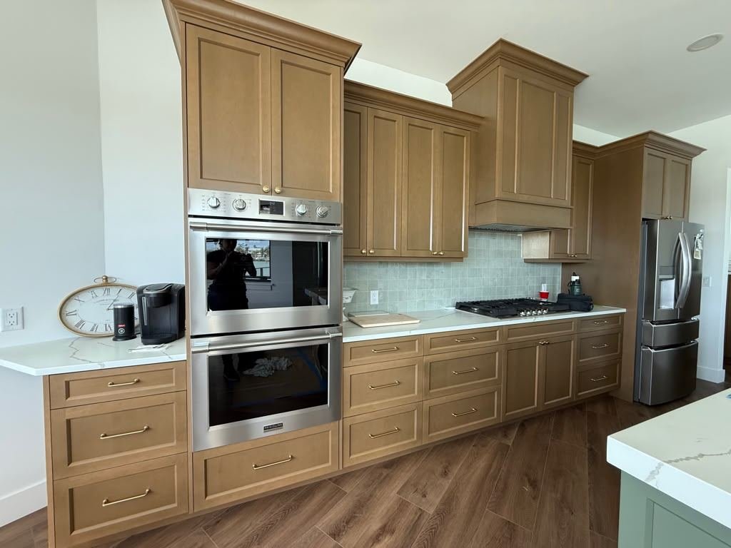 Newly built kitchen cabinetry finished in a warm stain, with a double wall oven