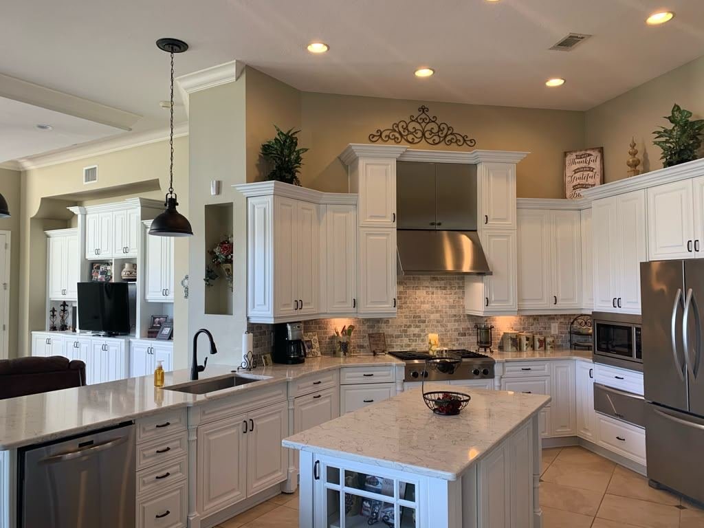 Newly built kitchen cabinetry painted white, with a quartz island